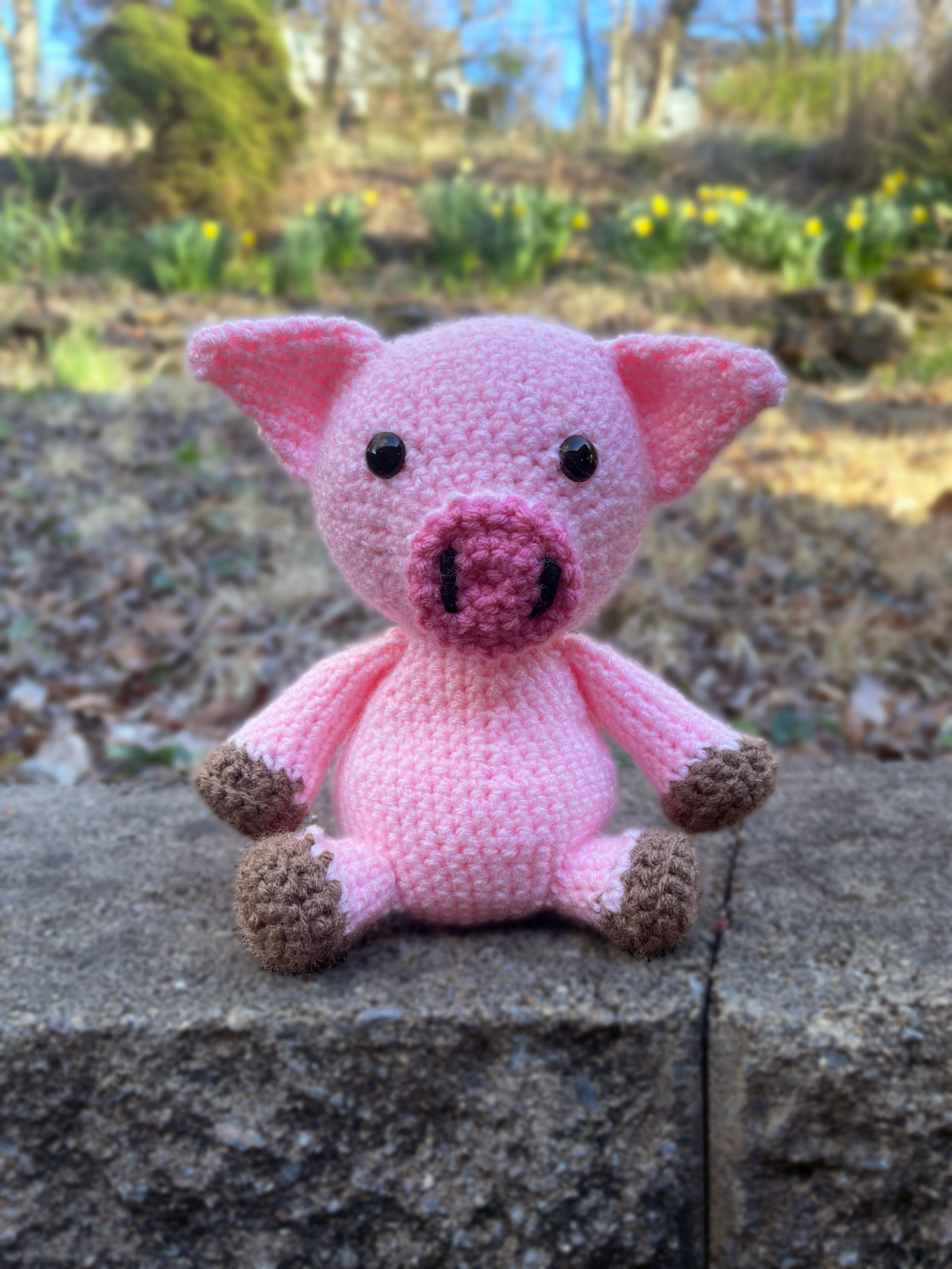 Pink Pig sitting on a stone slab with flowers in background